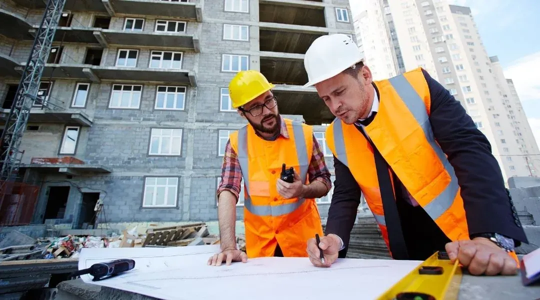 Dos personas revisando planos de construcción en terreno